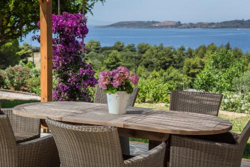 a wooden table with chairs and a vase with purple flowers at Panorama Fanari studios and apartments in Argostoli