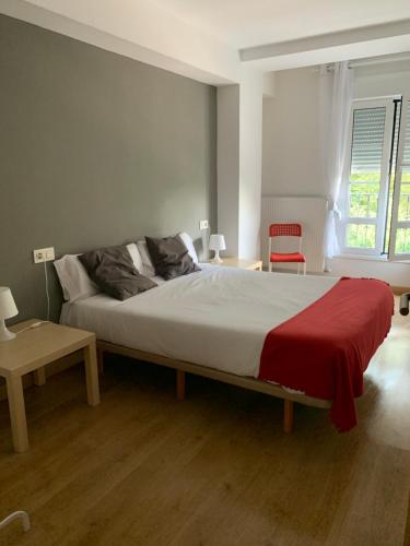 Un dormitorio con una cama grande con una manta roja. en APARTAMENTO LABEGAIN 2, en Sestao