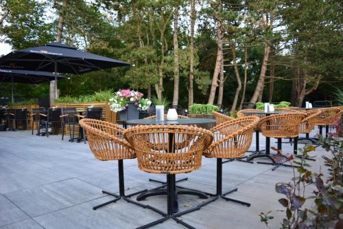 a group of chairs and a table with an umbrella at Fletcher Strandhotel Haamstede in Burgh Haamstede