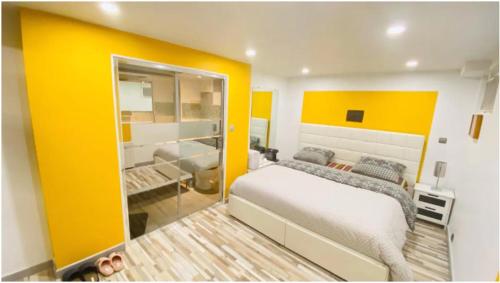 um quarto com uma cama grande e uma parede amarela em Chambre privée Cosy à proximité de Roissy, Parc Astérix em Fosses