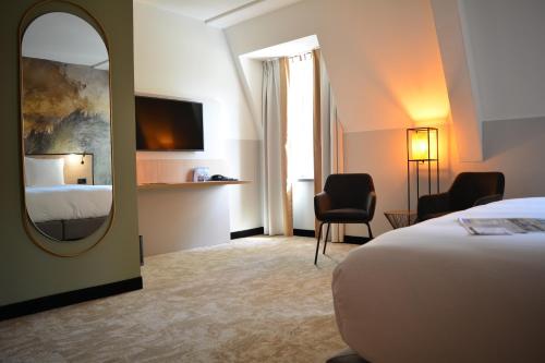 a hotel room with a bed and a mirror at Fletcher Strandhotel Haamstede in Burgh Haamstede