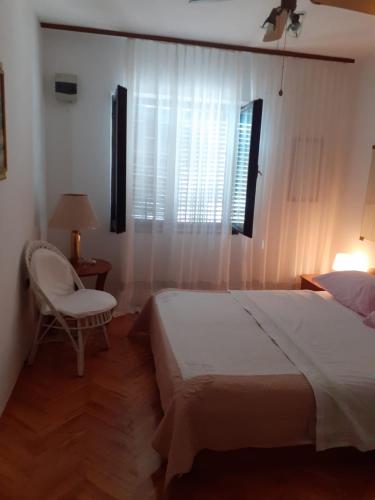 a bedroom with a bed and a chair and a window at Tisno Sea View apartment in Tisno