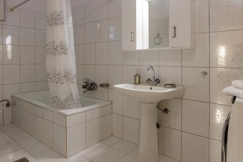 a white bathroom with a sink and a shower curtain at Nicole Fresh Apartments in Keramoti
