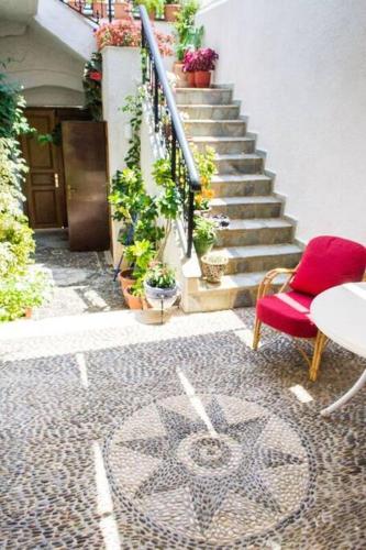 a red chair and a table and stairs with plants at Traditional House under Kazarma Fortress in Sitia in Sitia
