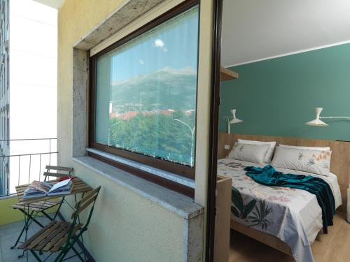 a bedroom with a bed and a large window at L'Atelier du Temps - Elvimo Apartment in Aosta