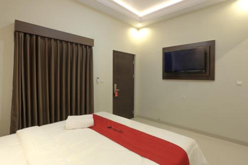 a bedroom with a bed and a flat screen tv at RedDoorz Plus near Solo Paragon Mall in Bonorejo