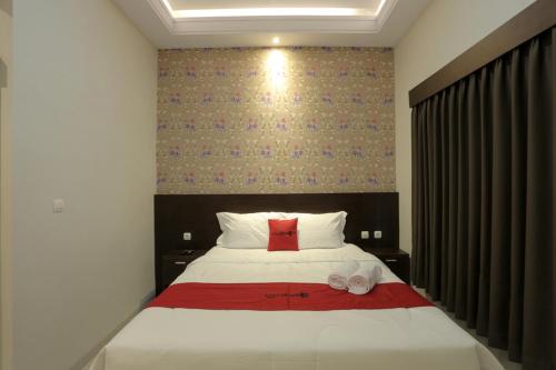 a bedroom with a bed with a red pillow and slippers at RedDoorz Plus near Solo Paragon Mall in Bonorejo