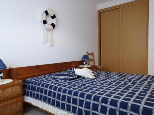 Zimmer mit einem Bett mit einer blau-weißen karierten Decke in der Unterkunft Armação de Pêra Praia Mar Sol in Armação de Pêra