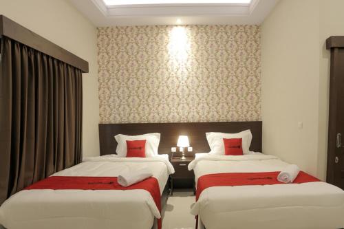 a hotel room with two beds with red sheets at RedDoorz Plus near Solo Paragon Mall in Bonorejo