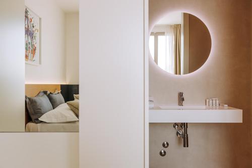 a bathroom with a sink and a mirror next to a bed at Miramare Blue Stay in Torre Santa Sabina