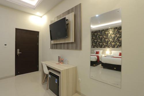 a hotel room with a bed and a television on the wall at RedDoorz Plus near Solo Paragon Mall in Bonorejo
