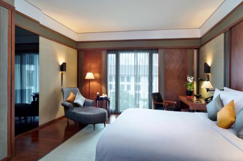 a hotel room with a bed and a chair at The Sukhothai Bangkok in Bangkok