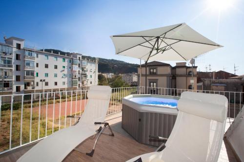 a balcony with a hot tub and chairs and an umbrella at Emma luxury room in Sorrento