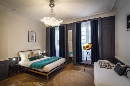een slaapkamer met een bed, een bank en een kroonluchter bij Hello Colmar Luxury Petite Venise 7 pers parking velos in Colmar
