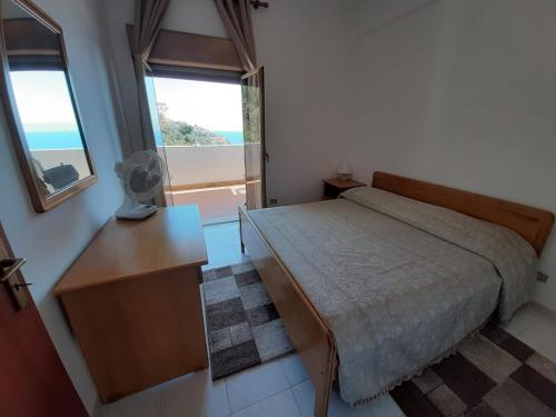 a bedroom with a bed and a desk and a window at Casa Yuliya in Letojanni