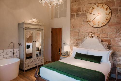 a bedroom with a bed and a bath tub and a clock at Newton Hall in Chathill