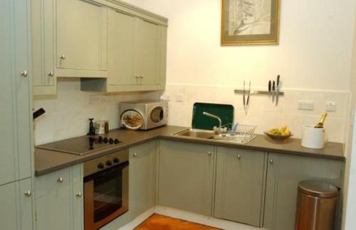 uma cozinha com armários brancos, um lavatório e um micro-ondas em Warwick Hall em Carlisle