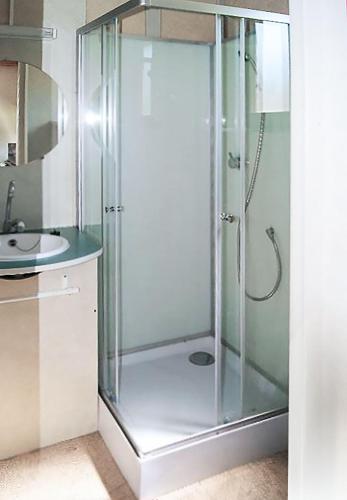 une douche en verre dans une salle de bain avec un lavabo dans l'établissement Du côté de chez Sam, à Andelaroche