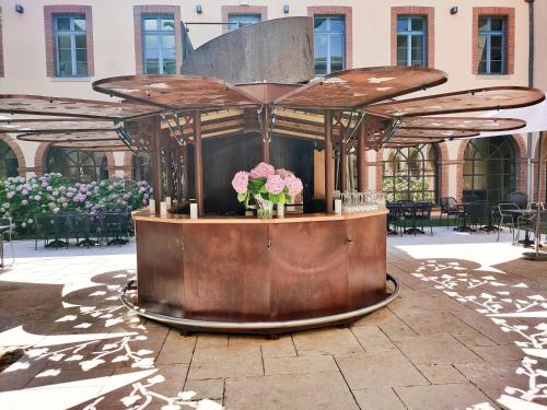 a large wooden structure with flowers on a patio at Abbaye des Capucins Spa & Resort in Montauban