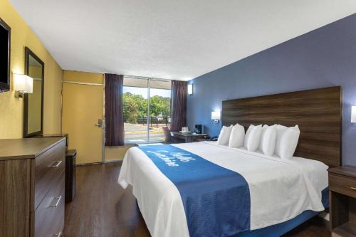 a hotel room with a bed and a large window at Days Inn by Wyndham Hampton Near Coliseum Convention Center in Hampton