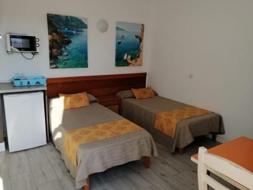 a hotel room with two beds and a tv at Apartamentos Arcadio in El Arenal