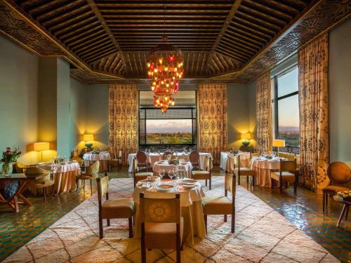 a dining room with tables and chairs and a chandelier at Fairmont Royal Palm Marrakech in Marrakech