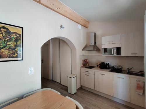 une cuisine avec des armoires blanches et une table en bois dans l'établissement Gîte Pavillon Arcadia, à Vaison-la-Romaine