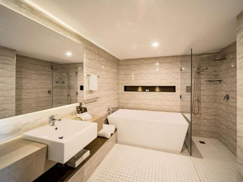 a bathroom with a sink and a tub and a shower at Novotel Wollongong Northbeach in Wollongong