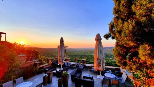 a patio with tables and umbrellas with the sunset in the background at Varosi 4 Seasons in Edessa