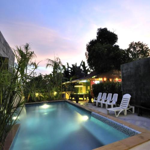 a swimming pool with chairs and a house at Serene Villa Phuket in Chalong