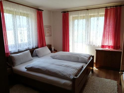 a bedroom with two beds and red curtains at Ferienwohnungen Panoramablick in Sankt Ulrich am Pillersee