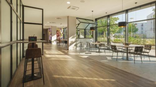 a lobby with tables and chairs and windows at Holiday Inn - the niu, Leo Nuremberg by IHG in Nürnberg