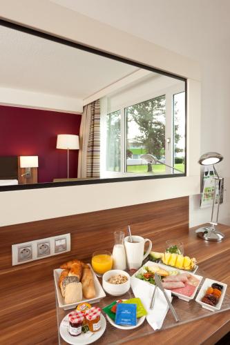 a breakfast table with food on it with a large mirror at Holiday Inn Lille Ouest Englos by IHG in Englos