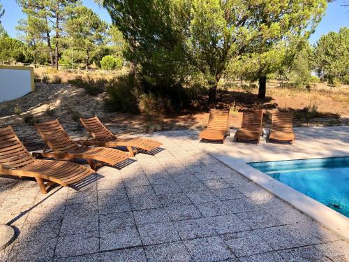 a group of lounge chairs next to a swimming pool at Villa Sal - Spacious, private Apartment in a Villa with pool in Alcácer do Sal