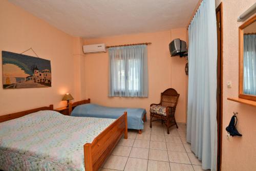 a bedroom with two beds and a chair and a window at Korinas House in Agnontas