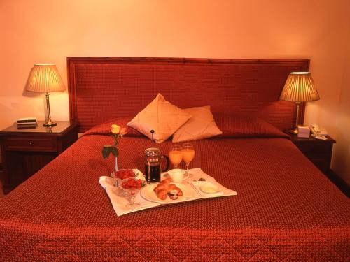 a tray of food on a bed with two drinks at The Grange at Oborne in Sherborne