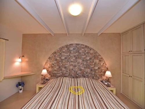 a bedroom with a large bed with a stone wall at TINOS AQUA PALAZZO in Tinos Town