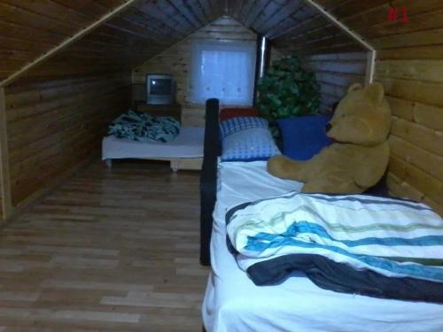 un osito de peluche sentado encima de dos camas en una habitación en Domek letniskowy Szramowo, en Szramowo