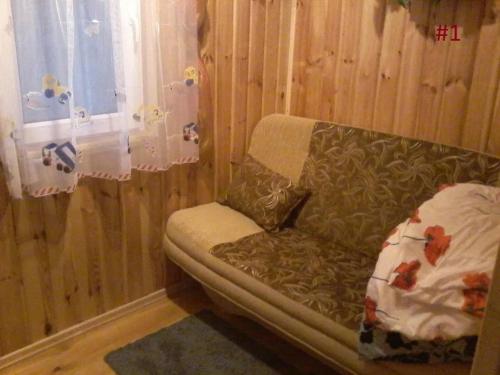 um sofá sentado num quarto com uma janela em Domek letniskowy Szramowo em Szramowo