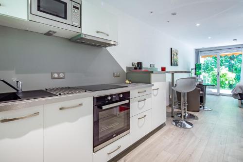 a kitchen with white cabinets and a stove top oven at Wellholidays 19 - Balnéo, terrasse et piscine partagée in Boersch