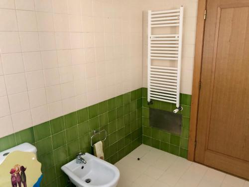 a green and white bathroom with a sink and a toilet at Villa Sal - Spacious, private Apartment in a Villa with pool in Alcácer do Sal