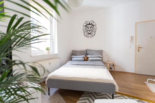 - un lit dans une chambre blanche avec une plante dans l'établissement FULL HOUSE Studios - Lion Apartment - WiFi inkl, à Halle-sur-Saale