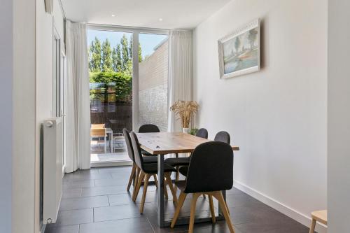 een eetkamer met een tafel en stoelen en een raam bij Maison Clos in De Panne
