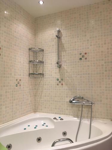a white bath tub in a tiled bathroom at A1 Elegant Vouliagmeni apt in a Unique Spot in Athens