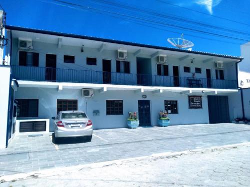 um carro estacionado em frente a um edifício branco em Hotel Pousada Garoupas em São Sebastião