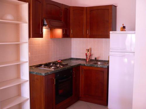 een keuken met houten kasten, een fornuis en een koelkast bij Trilocale Alba Adriatica a 500 m dal mare in Alba Adriatica