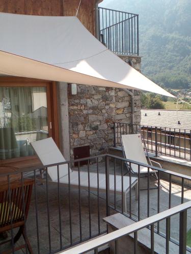 a balcony with tables and chairs and a white umbrella at merian in Piuro