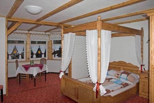 a bedroom with a canopy bed and a table at Hotel Waldoase Hirschbüchenkopf in Güntersberge