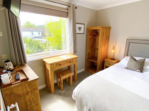 a bedroom with a bed and a window at Cairngorm Guest House in Aviemore
