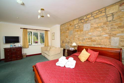 a bedroom with a red bed with towels on it at The Grange at Oborne in Sherborne